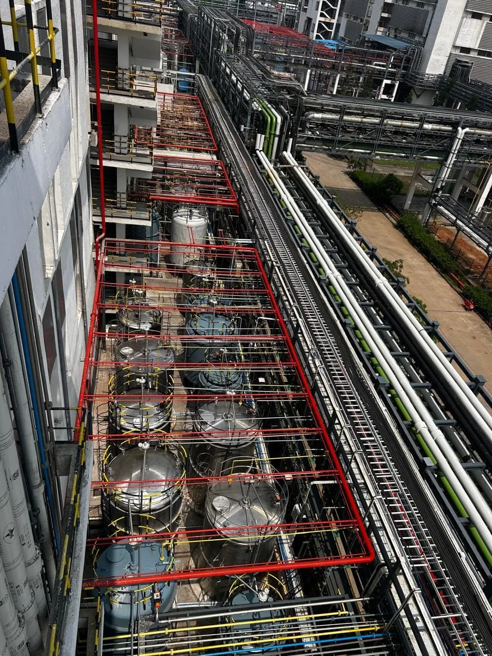 Rooftop view along a pipe rack, vessel rows and utility lines running the length of a process block